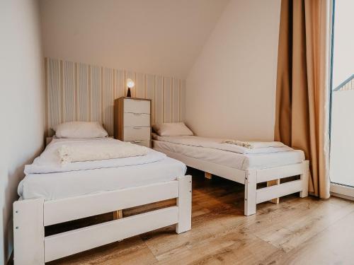 a bedroom with two white beds and a window at Holiday Home by Lake arnowieckie with Jacuzzi in Nadole