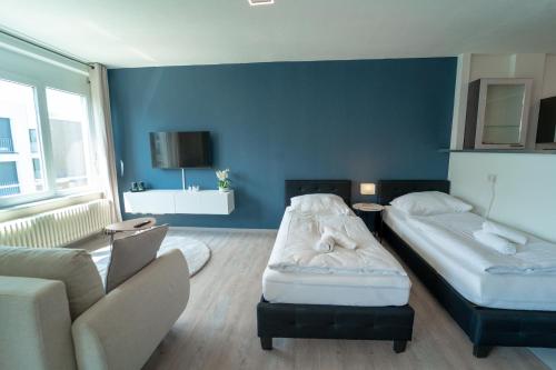 a blue room with two beds and a couch at RANGE - Apartments - Küche - WLAN - Netflix - 1-7 Personen in Fellbach