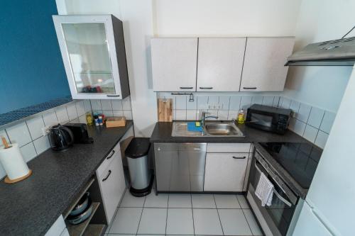 a small kitchen with white cabinets and a sink at RANGE - Apartments - Küche - WLAN - Netflix - 1-7 Personen in Fellbach
