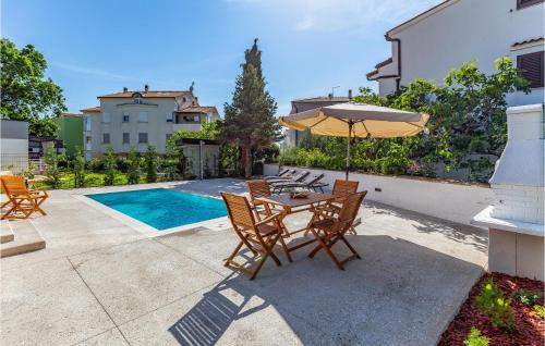 taras ze stołem, krzesłami i parasolem w obiekcie Pet Friendly Apartment In Madulin w Medulinie