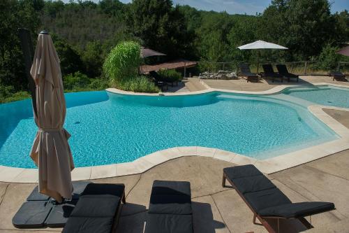 a swimming pool with an umbrella and two chairs and a umbrella at Aux lodges du mas de Nadal in Sauliac-sur-Célé