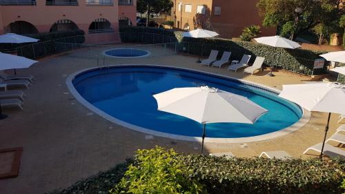 - une piscine avec des parasols et des chaises longues dans l'établissement Résidence les jardins de la mer 20230 marine de bravonne, à Linguizzetta