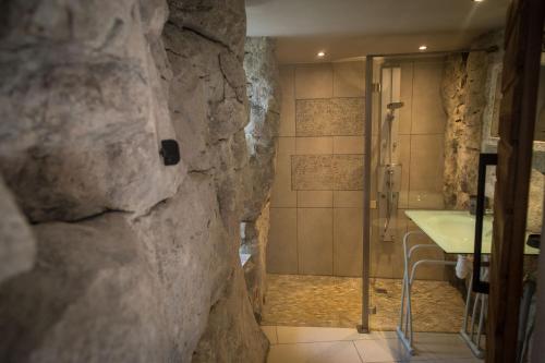 La salle de bains en pierre est pourvue d'une douche et d'un lavabo. dans l'établissement Hébergement insolite en pleine nature & piscine 2 à 11 p - Gites Les Princes à LANAS, à Lanas