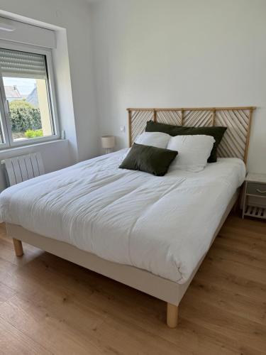 une chambre avec un lit avec des draps blancs et une fenêtre dans l'établissement TREVIGNON - Ty Bihan Anna, à Trégunc