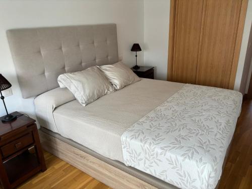a bedroom with a white bed and a night stand at Portosin Sea&Pool in Portosin