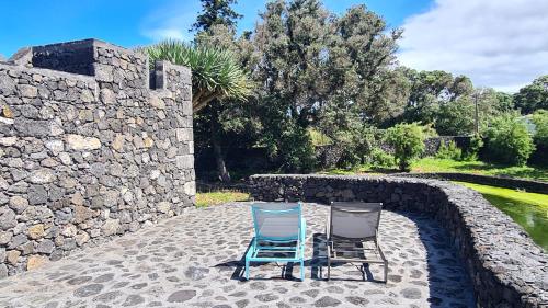two chairs sitting on a patio next to a stone wall at Solar dos limas in Criação Velha