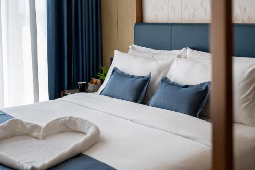 a white bed with blue and white pillows at Copper Leaf Hotels, Tirunelveli in Tirunelveli