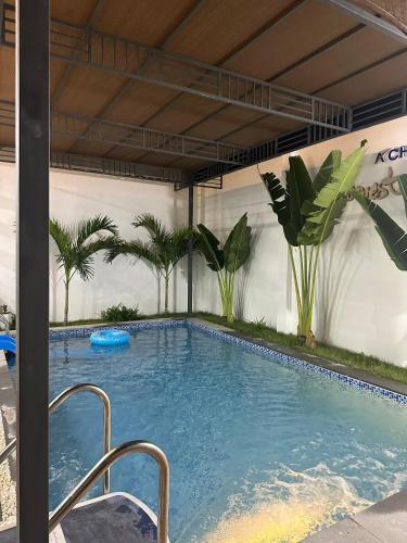 a large swimming pool with palm trees in a building at Á Châu homestay in Ấp Thanh Sơn (1)