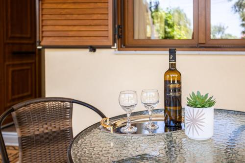 a bottle of wine sitting on a table with two wine glasses at Nelly's Place Garden house 2 in Zakharo