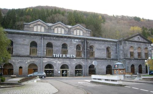 un grand bâtiment en pierre avec une voiture garée devant dans l'établissement Studio MARMOTTES au RDC a HYPER centre du Mont DORE, à Mont-Dore