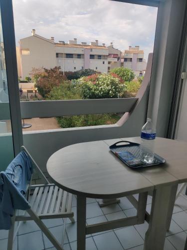d'une table et d'une chaise sur un balcon avec une fenêtre. dans l'établissement Appartement au calme T2 refait à neuf, 2 vélos, avec 2 piscines, 400 m de la mer, au Grau-du-Roi