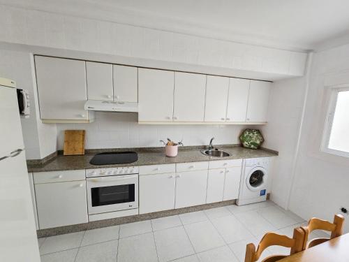 Una cocina blanca con gabinetes blancos y un fregadero. en Acogedor Apartamento, en Vilagarcía de Arousa