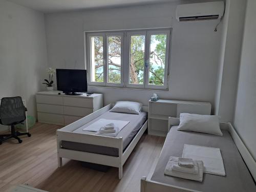 a white room with two beds and a tv at NoAr Apartment Rijeka in Rijeka