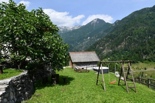 a playground in a field with a house and mountains at Apartment Abinkar in Tolmin