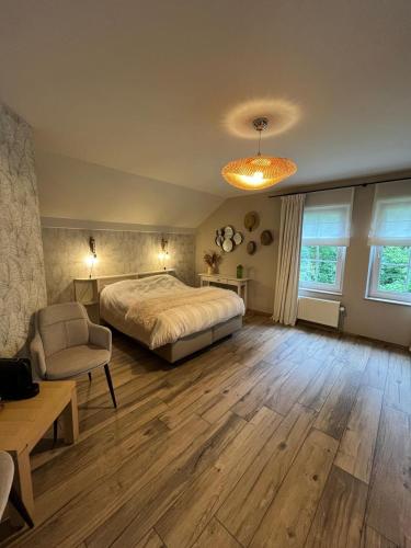 a large bedroom with a bed and a chair at L'envie d'ailleurs in Malmedy