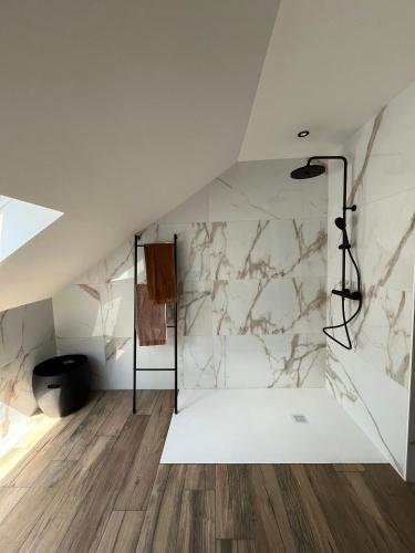 a bathroom with white marble walls and wooden floors at L'envie d'ailleurs in Malmedy