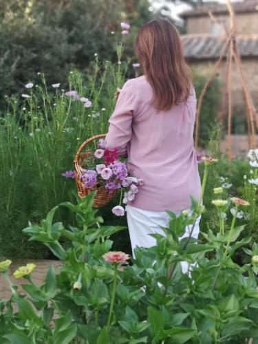 a woman holding a basket of flowers in a garden at Villa di Piazzano - Small Luxury Hotels of the World in Cortona