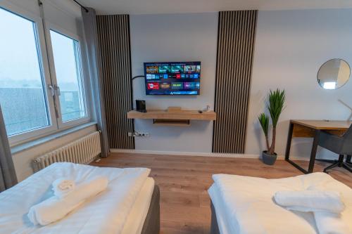 a hotel room with two beds and a flat screen tv at RANGE - Apartments - Küche - WLAN - Netflix - 1-7 Personen in Fellbach