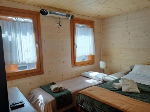 two beds in a room with two windows at Nido Ampezzano in Borca di Cadore