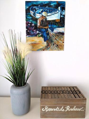 a vase with a plant in it next to a painting at Maison familiale proche de la mer in Lancieux