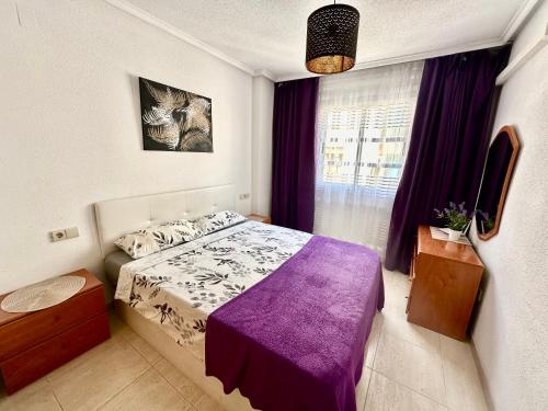 a bedroom with a bed with a purple blanket at La Loma 72 in Torrevieja