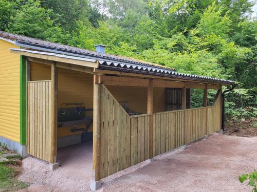 a wooden garage with a fence and trees at Ormanäsgårdens Stugby in Höör