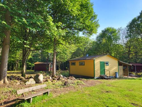 a yellow shed with a bench in a yard at Ormanäsgårdens Stugby in Höör