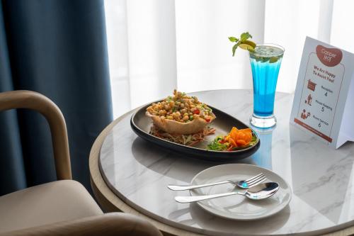 a table with a plate of food and a drink at Copper Leaf Hotels, Tirunelveli in Tirunelveli