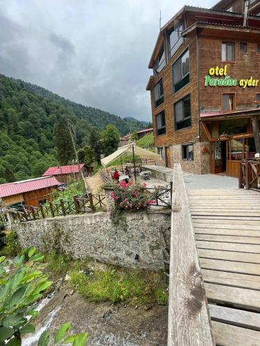 a building with a wooden bridge and benches and flowers at Ayder Paradise Otel in Ayder Yaylasi