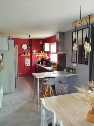 une cuisine avec des murs rouges et une table et des chaises dans l'établissement Maison Centre bourg, à Nort-sur-Erdre