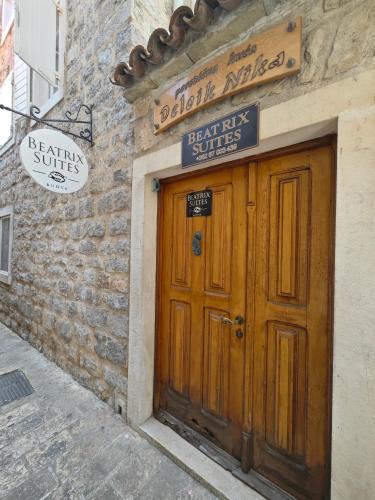 a building with a wooden door and a sign above it at Beatrix Suites in Budva
