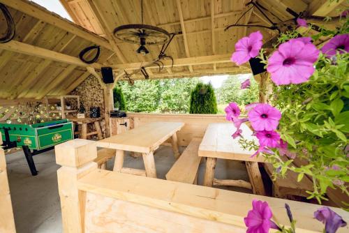 a patio with wooden tables and pink flowers at CICHY ZAKĄTEK - noclegi blisko Termy Chochołowskie in Ciche
