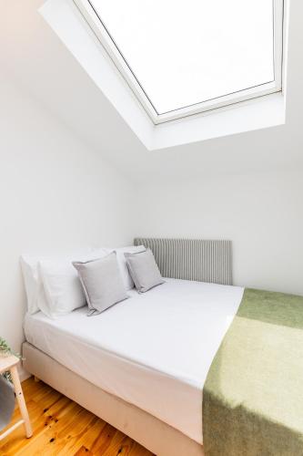 a bed in a room with a skylight at A Window to Porto - Pestana charming flat in Porto