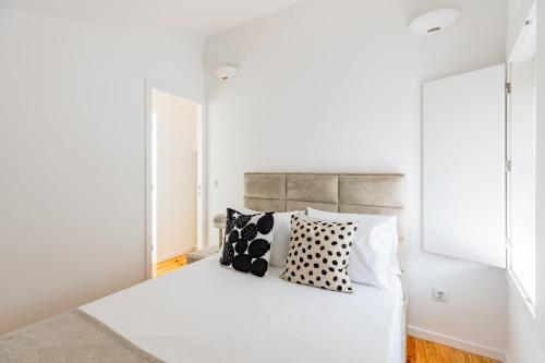a bedroom with a white bed with black and white pillows at A Window to Porto - Pestana charming flat in Porto
