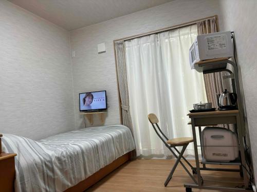 a bedroom with a bed and a tv and a window at Guest House Harukawa in Osaka