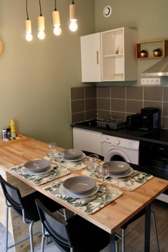 einen Tisch mit Tellern und Gläsern darauf in der Küche in der Unterkunft Cocon Bourguignon in Villers-la-Faye