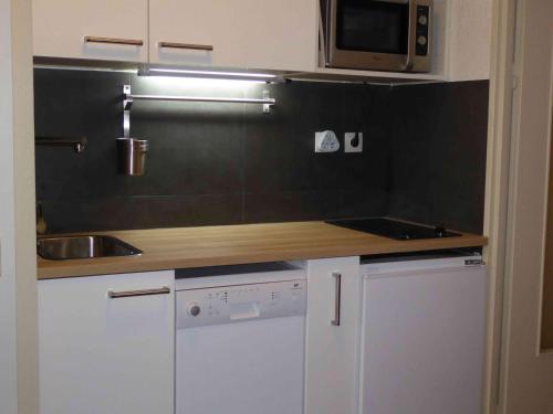 une petite cuisine avec un évier et un micro-ondes dans l'établissement Studio port Hyères 200m mer parking privé, à Hyères