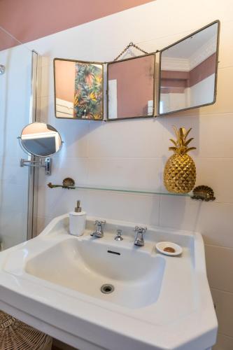 une salle de bain avec un lavabo blanc et deux miroirs dans l'établissement Les deux clefs acte 2, à Mont-de-Marsan