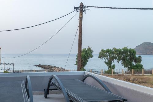 a bench on a balcony with a view of the water at Platanias Aetheras Beach in Plataniás