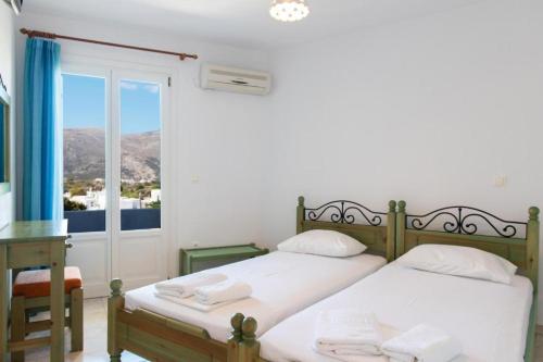 a bedroom with two beds and a desk and a window at Alekos Studios Artemonas in Artemonas