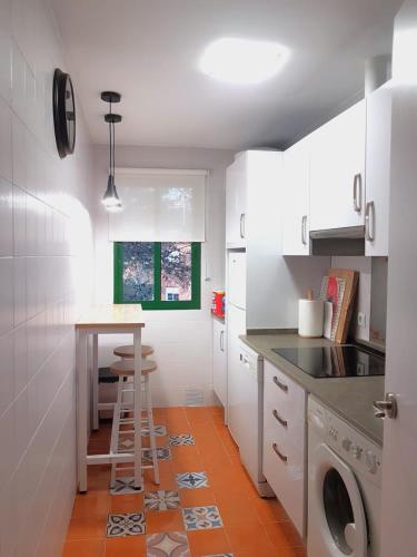 a kitchen with white cabinets and a table and a stool at Vistahermosa-El ancla in El Puerto de Santa María
