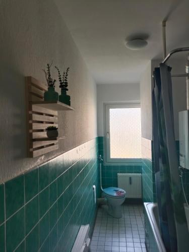 a bathroom with a toilet and a window and green tiles at Nette Kuschelige Terrassen Wohnung in Bochum