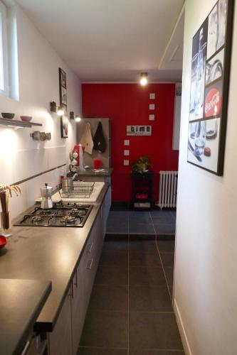 - une cuisine avec une cuisinière et un mur rouge dans l'établissement Maison de ville avec jardin à 2 pas des Marais et quelques mns du centre-ville, à Bourges