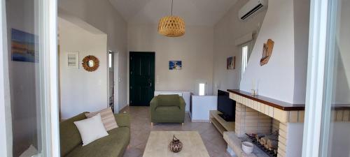 a living room with a fireplace and a green chair at Mpatsi Sunset House in Batsi