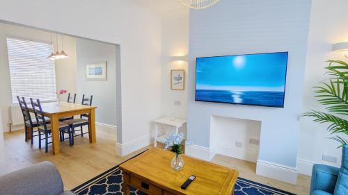 a living room with a table and a tv on a wall at Sea Breeze House in Scarborough
