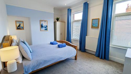 a bedroom with blue curtains and a bed and a chair at Sea Breeze House in Scarborough