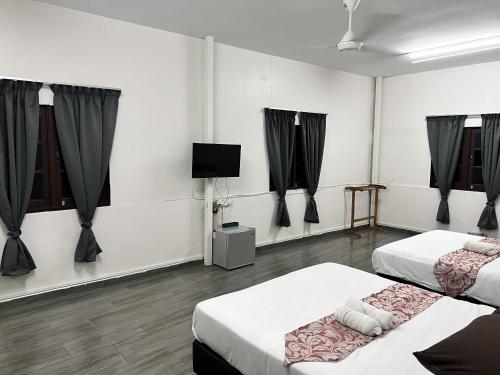 パダン・ブサールにあるPadang Besar Green Innの黒いカーテンとテレビのある部屋にベッドが2つある