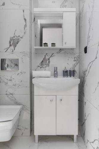 a white bathroom with a sink and a mirror at Live The Luxe in Kallithea Halkidikis