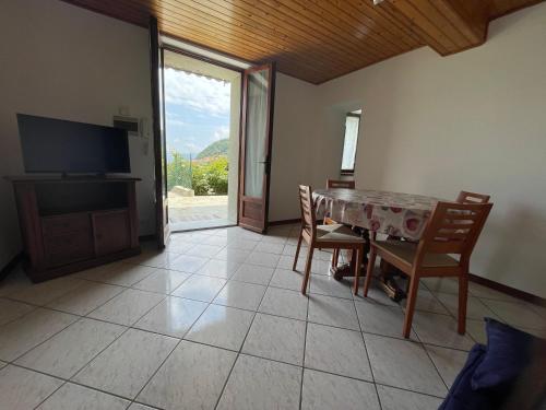 a dining room with a table and chairs and a television at Casa Luca in Plesio