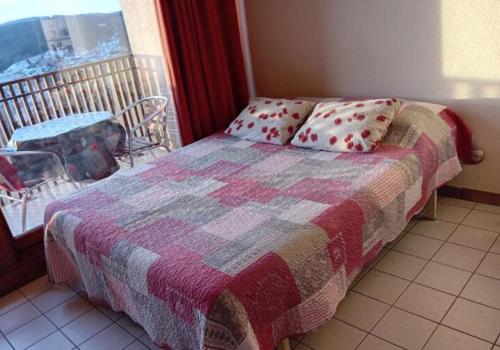 une chambre avec un lit avec une couverture et une fenêtre dans l'établissement Studio les bleuets, à Gérardmer